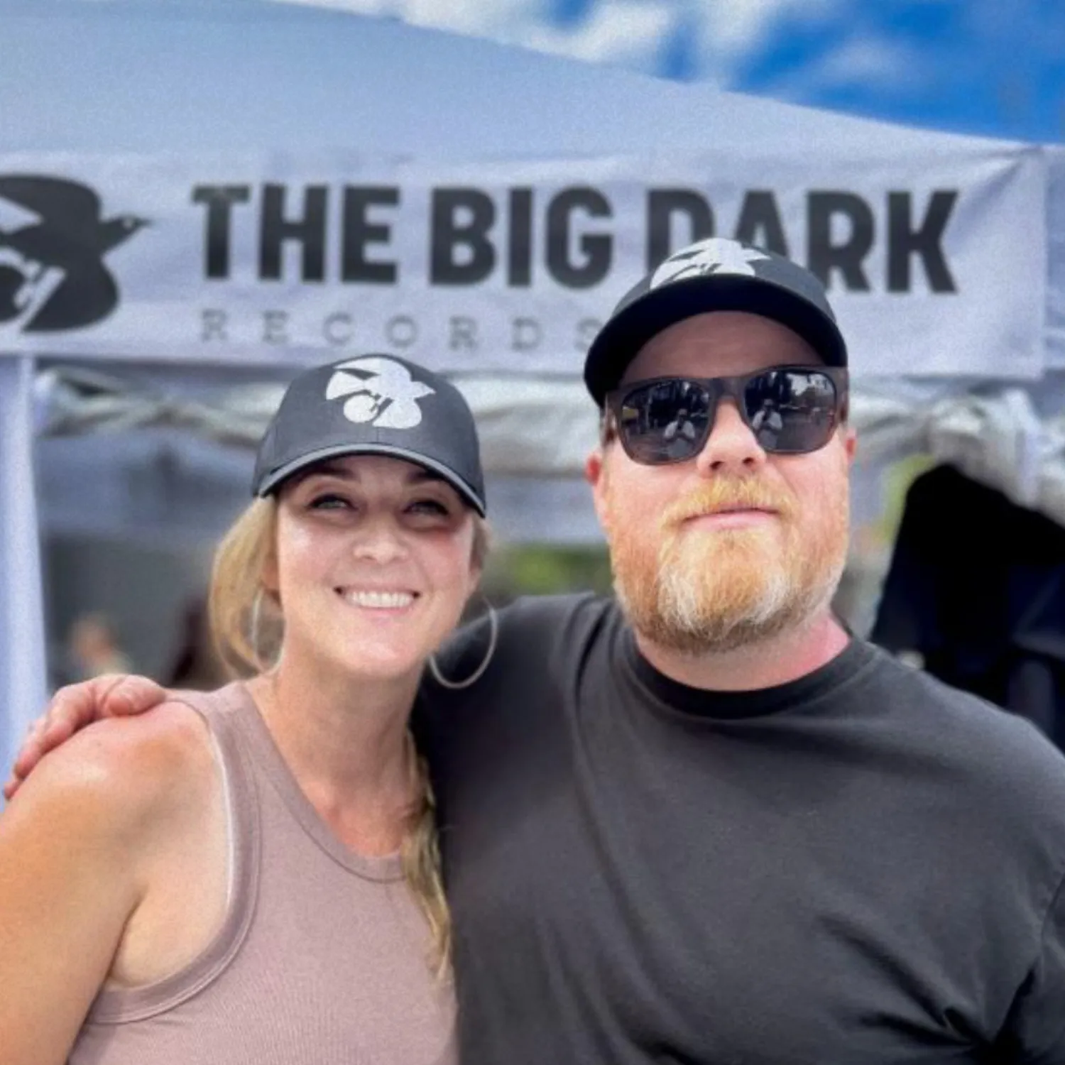Magen and Kellen Holgate in Big Dark Records caps, smiling in front of the label's tent.
