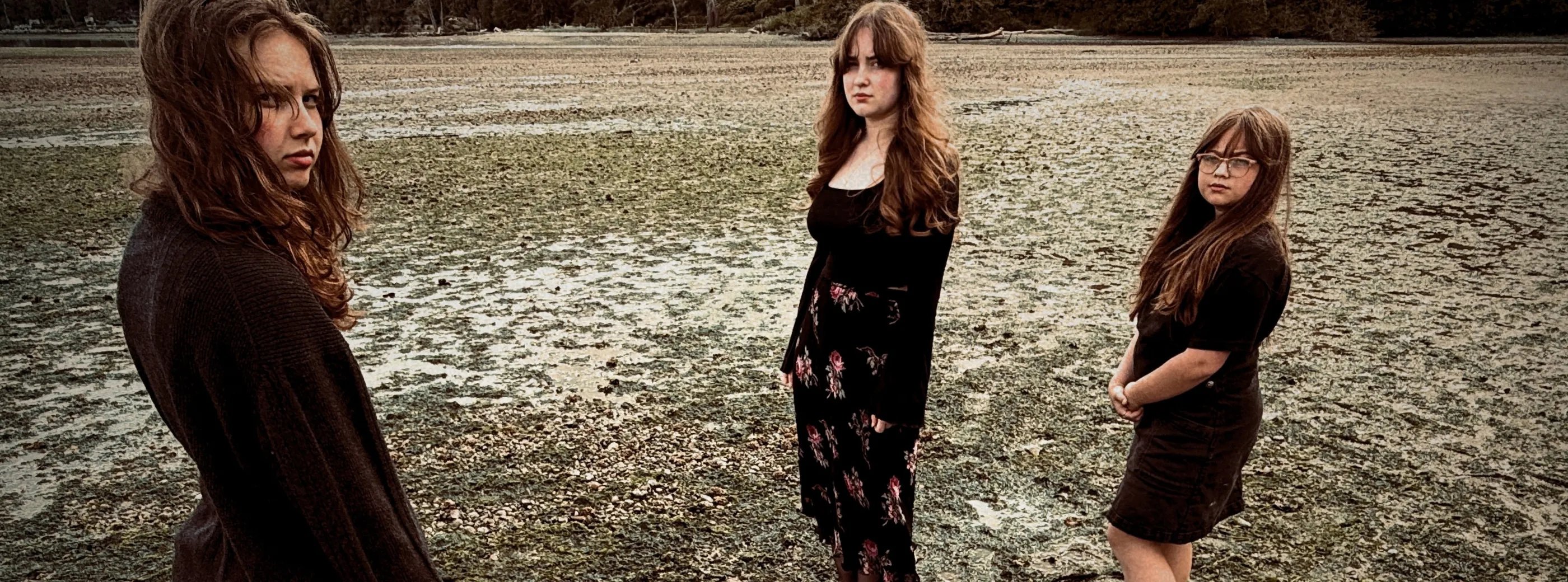 The three members of Sad Dad Autumn standing on a muddy tide flat.